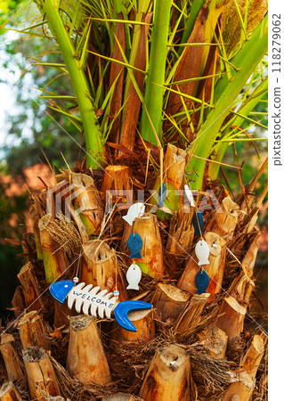 wooden garden decor in the shape of fish on a palm tree in a charming garden wooden garden decor in the shape of fish on a palm tree in a charming garden 118279062