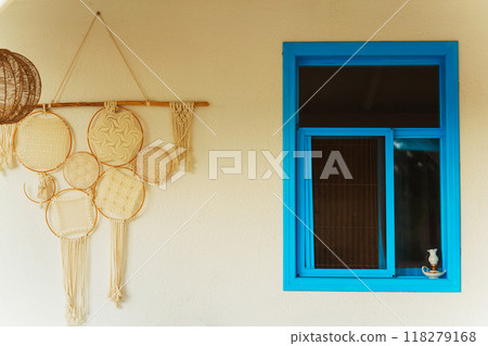 A blue window and a unique dream catcher on a rustic wall 118279168