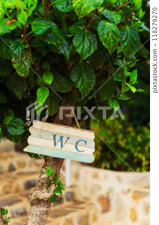 A wooden sign hanging from a tree that says wc  118279270
