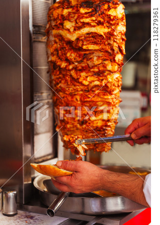 A person is holding a piece of bread right in front of a kebab machine A person is holding a piece of bread right in front of a kebab machine 118279361