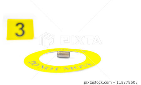 A spent bullet casing placed within a yellow circle, labeled with the text "Evidence, Do Not Move," with a blurred number 3 tag, set against a white background, concept of crime investigation. A spent bullet casing placed within a yellow circle, labeled with the text "Evidence, Do Not Move," with a blurred number 3 tag, set against a white background, concept of crime investigation. 118279605