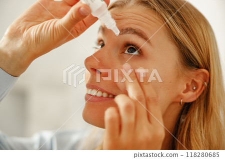 A woman is applying eye drops to achieve relief and hydration for her eyes comfort A woman is applying eye drops to achieve relief and hydration for her eyes comfort 118280685