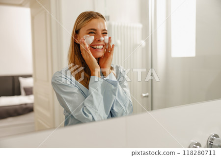 A woman is enjoying her revitalizing morning skincare routine while in the bathroom A woman is enjoying her revitalizing morning skincare routine while in the bathroom 118280711