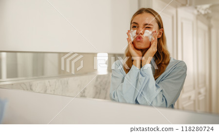 A Woman Happily Enjoying Her Skincare Routine in a Stylish and Modern Bathroom Setting 118280724