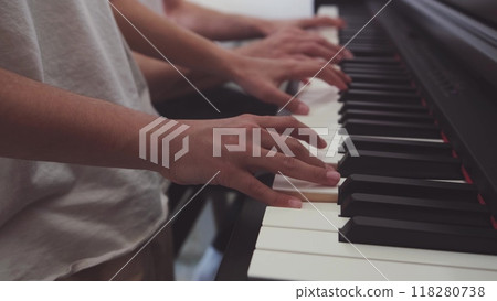 A teenage pianist and her dad play the piano, touching their fingers to the black and white keys to create the rhythm of the melody. People. Child development and entertainment. Art. Education A teenage pianist and her dad play the piano, touching their fingers to the black and white keys to create the rhythm of the melody. People. Child development and entertainment. Art. Education 118280738