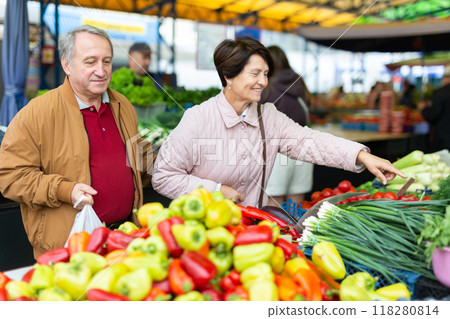 Happy mature male and female picking fresh organic vegetables during shopping at local bazaar 118280814