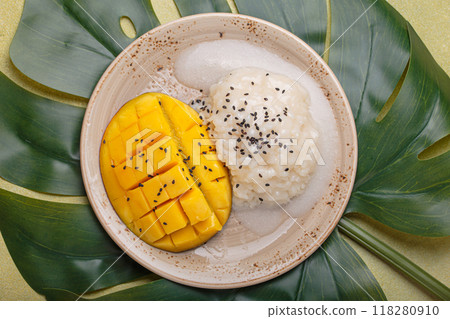 Traditional dessert of Thailand, delicious mango sticky rice with coconut milk and sesame seeds on tropical leaf top view 118280910
