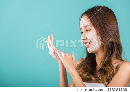 Portrait Asian young woman hands are adorned with white foam cleaning face studio shot isolated on blue background, beautiful female holds a cleansing foam on palm, Cosmetics beauty skincare 118281188