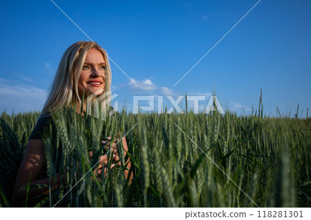 Smiling female Farmer standing on Wheat Fields and looking forward Smiling female Farmer standing on Wheat Fields and looking forward 118281301