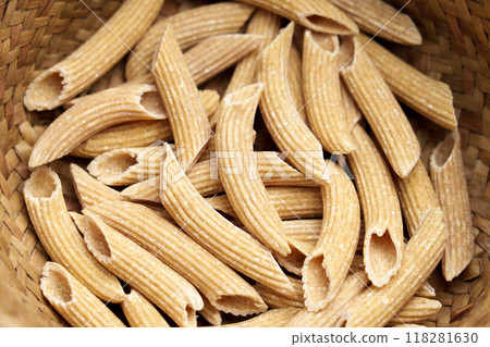 Whole Grain quinoa gluten free uncooked penne pasta in kitchen rustic wicker bowl. Dieting organic ingredients. Macro Whole Grain quinoa gluten free uncooked penne pasta in kitchen rustic wicker bowl. Dieting organic ingredients. Macro 118281630