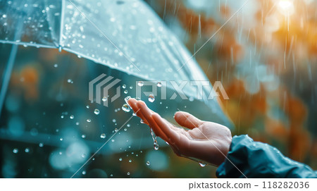 Hand Catching Raindrops Under an Umbrella on a Rainy Day 118282036