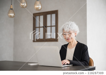 Business image of a beautiful senior (elderly) woman with gray hair looking down and typing on a computer 118287389