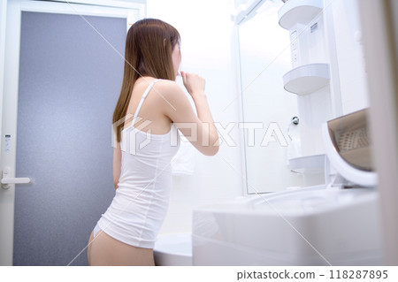 Young woman brushing her teeth in the bathroom in the morning, brushing teeth, getting ready to go out, camisole Young woman brushing her teeth in the bathroom in the morning, brushing teeth, getting ready to go out, camisole 118287895