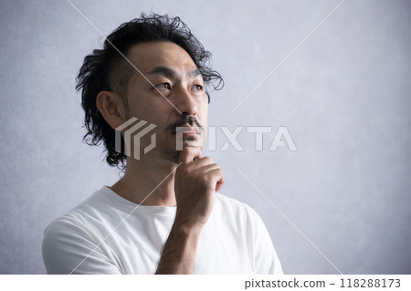 Close-up of a bearded man thinking on a grey background Close-up of a bearded man thinking on a grey background 118288173