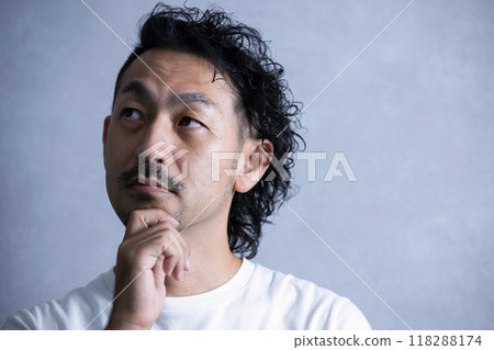 Close-up of a bearded man thinking on a grey background 118288174