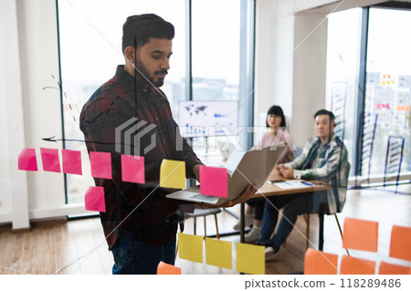 Team brainstorming session with sticky notes and laptop in office Team brainstorming session with sticky notes and laptop in office 118289486
