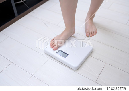 Woman weighing herself, feet on the scale 118289759