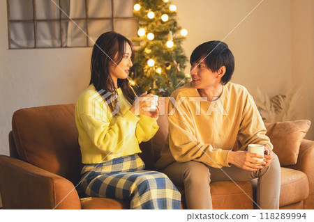 A young couple relaxing in a room decorated with a Christmas tree A young couple relaxing in a room decorated with a Christmas tree 118289994