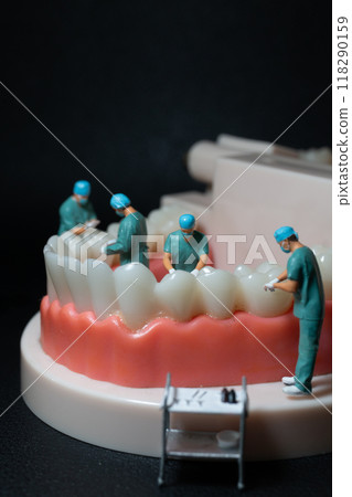Miniature figurines of surgeons working on a large model of human teeth Miniature figurines of surgeons working on a large model of human teeth 118290159
