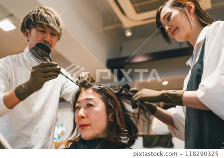 Two hairdressers dyeing gray hair 118290325