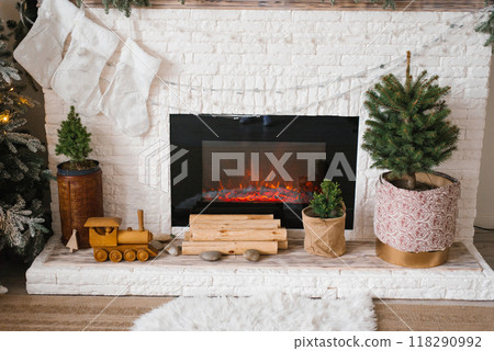 Fireplace with a train set and a potted christmas tree in front of it Fireplace with a train set and a potted christmas tree in front of it 118290992