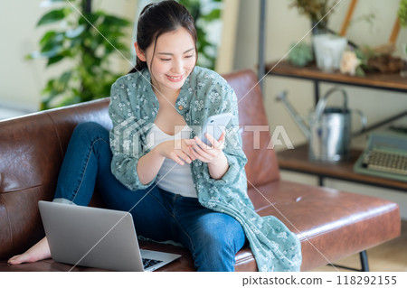 A young woman looking at a computer in the living room 118292155