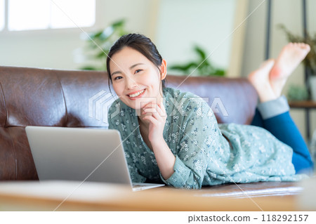 A young woman looking at a computer in the living room 118292157