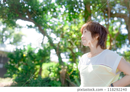 一個微笑的女人在新鮮的綠色植物中仰望天空 118292240