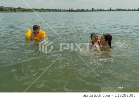 Mom and kids enjoying a summer day at the lakes, swimming and diving in the water. A cheerful and carefree summer day by the lake 118292395