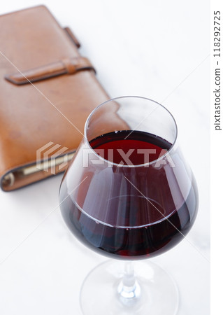 Image of a person writing a diary in a brown leather organizer while drinking red wine Image of a person writing a diary in a brown leather organizer while drinking red wine 118292725