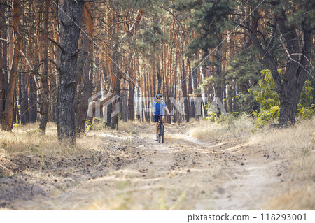 woman cyclist rides in the pine forest on a mountain bike. 118293001