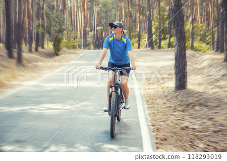 woman cyclist rides in the forest on a bike. 118293019