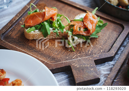 Sandwich with red fish and green salad on a wooden tray. Sandwich with red fish and green salad on a wooden tray. 118293020