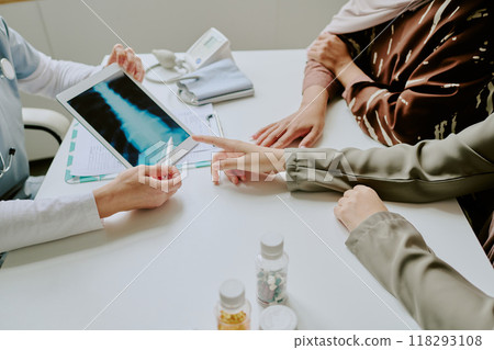 Medical professional showing x-ray results to patient in consultation room. Focus on discussing treatment options and diagnosis during appointment Medical professional showing x-ray results to patient in consultation room. Focus on discussing treatment options and diagnosis during appointment 118293108