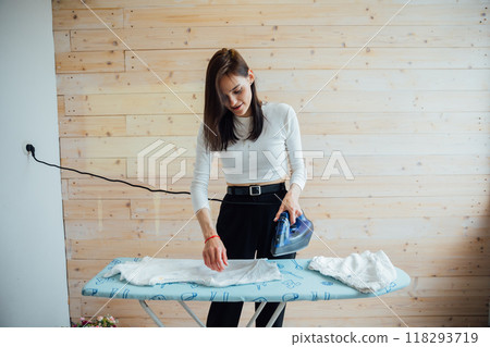 Woman housewife ironing clothes with iron in bedroom Woman housewife ironing clothes with iron in bedroom 118293719