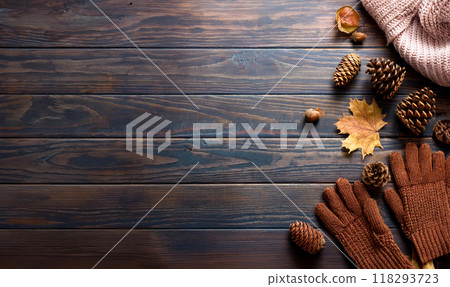 Autumn image background: knitted scarf, gloves, fallen leaves, pine cones and acorns 118293723