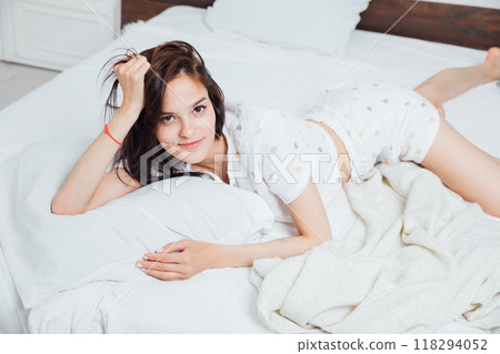 Beautiful slender woman in pajamas lying in bedroom on bed 118294052