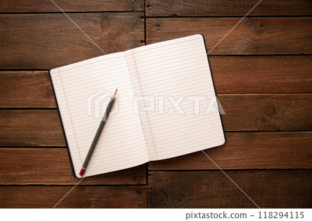 Open notebook and pencil on a rustic wooden board 118294115