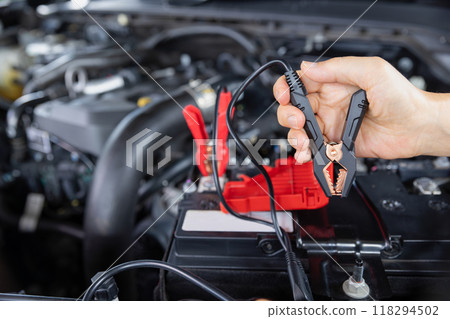 Senior Woman is jumping charger cable to AGM battery on car. Senior Woman is jumping charger cable to AGM battery on car. 118294502