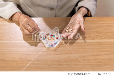 Elderly woman putting pills into pill box for the week. 118294522