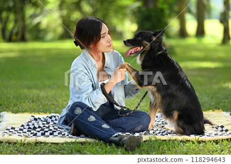 Happy young woman playing and enjoying time with her Border Bollie dog in a park. Outdoor activities, pet care and wellness concept 118294643