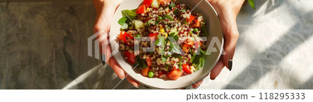 Hands holding a bowl of fresh, colorful quinoa salad with vegetables, perfect for a healthy and nutritious meal. Hands holding a bowl of fresh, colorful quinoa salad with vegetables, perfect for a healthy and nutritious meal. 118295333