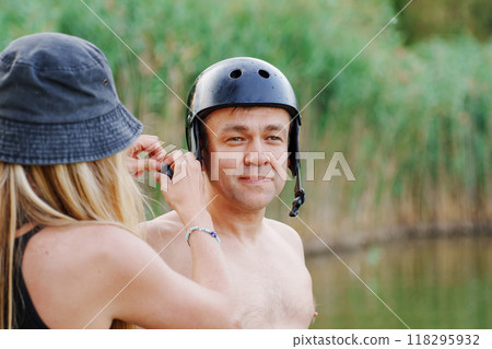 A middle-aged man puts on wakeboarding gear.  118295932