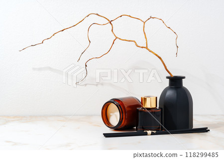 Brown Glass Candle and Diffuser Bottles on Marble Surface With Dried Branches 118299485