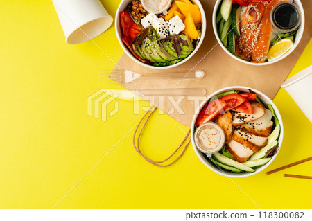 Top view of fresh poke bowls on yellow background 118300082
