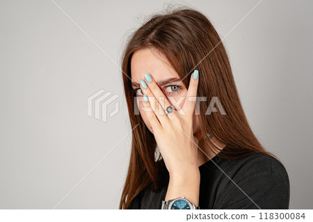 Young Woman Covering Face With Hands in Studio Young Woman Covering Face With Hands in Studio 118300084