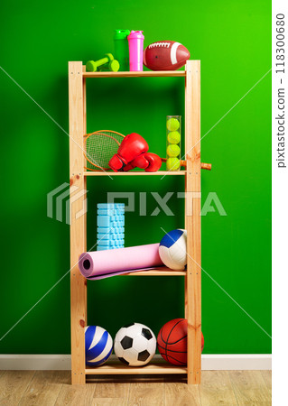 Shelves with different sports equipment against green wall Shelves with different sports equipment against green wall 118300680