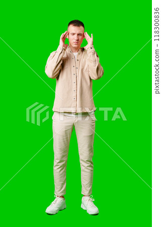 Man With Short Hair Wearing Beige Jacket Holding His Head in Frustration Against a Bright Green Background 118300836