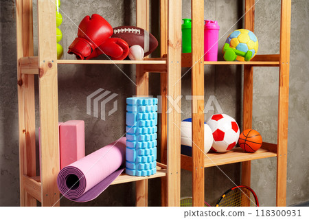Shelves with different sports equipment against green wall 118300931