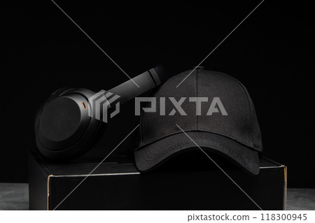 Baseball cap with black headphones on dark background Baseball cap with black headphones on dark background 118300945